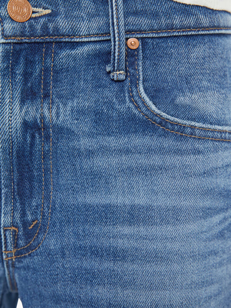 Swatch view of a woman in a mid blue mid-rise jeans with a loose fit, wide leg, zip fly and ankle-length inseam with a clean hem.