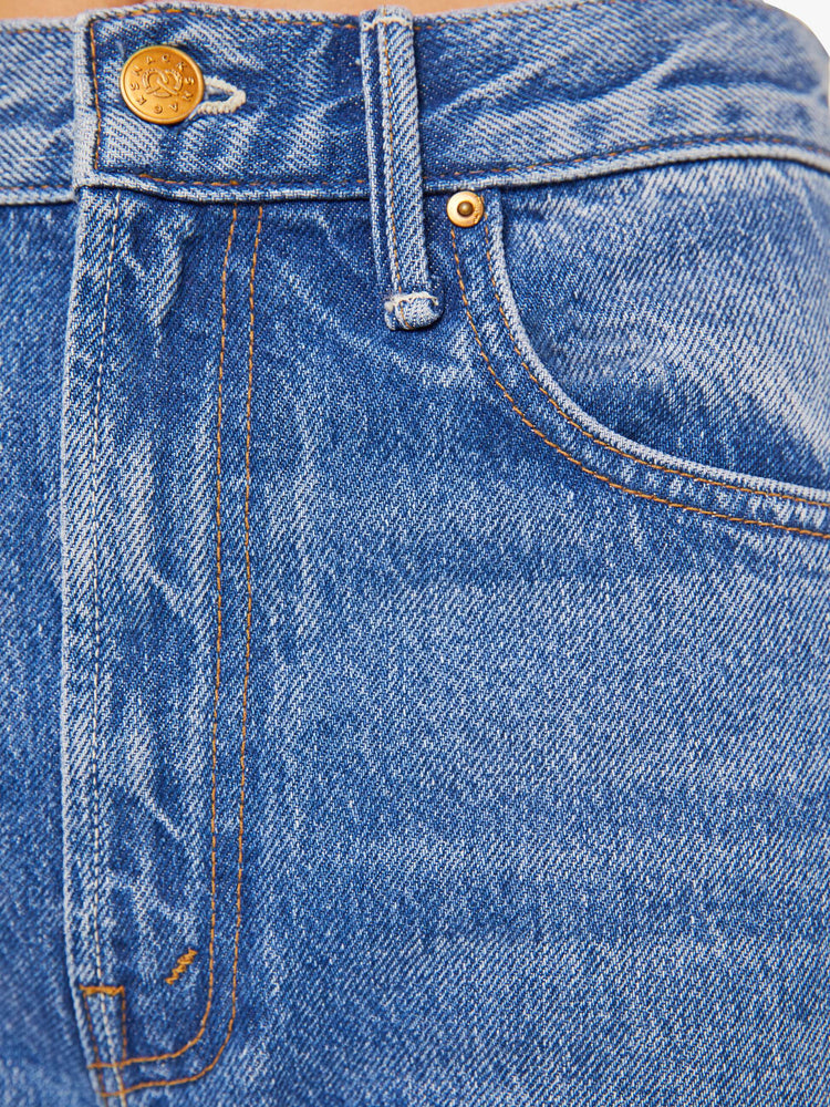 Swatch view of  woman in a mid blue high waisted jean with a wide leg  with a curved outer seam and a long 33.5-inch inseam with a clean hem. 