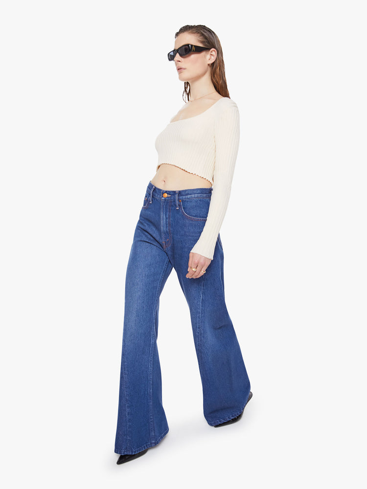 Walking view of woman in a mid blue super high rise jeans have a zip fly, loose wide leg with a curved outer seam and a long inseam with a clean hem.