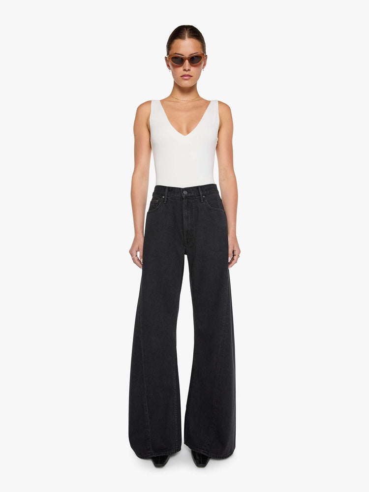 Front view of  woman in a black high waisted jean with a wide leg  with a curved outer seam and a long 32 inch inseam with a clean hem.