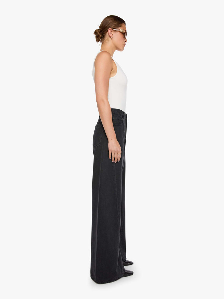 Side view of  woman in a black high waisted jean with a wide leg  with a curved outer seam and a long 32 inch inseam with a clean hem.