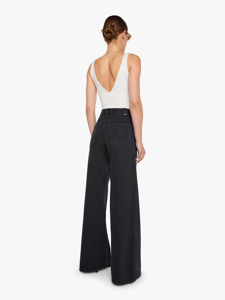 Back view of  woman in a black high waisted jean with a wide leg  with a curved outer seam and a long 32 inch inseam with a clean hem.