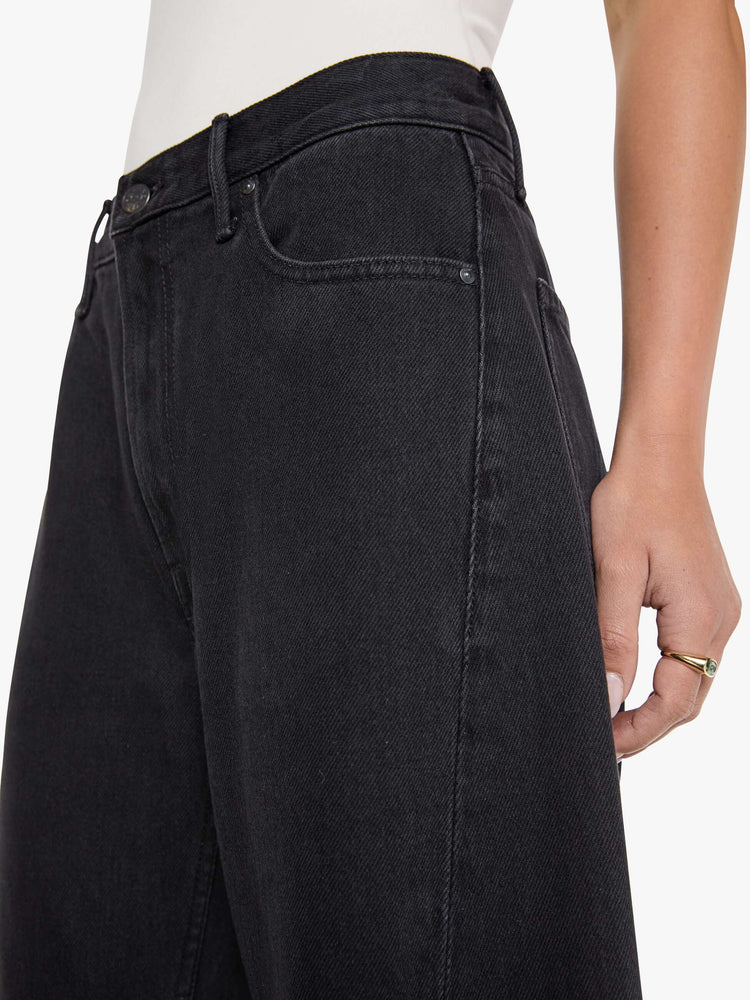 Close up view of  woman in a black high waisted jean with a wide leg  with a curved outer seam and a long 32 inch inseam with a clean hem.