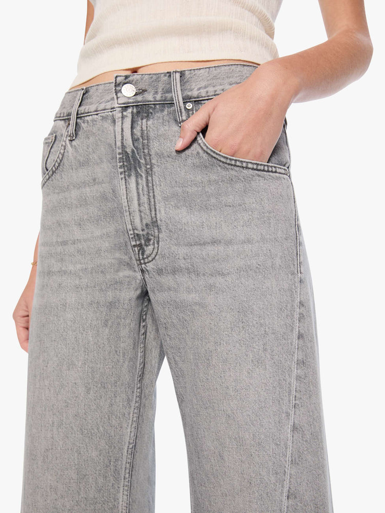 Close up view of a woman in a washed grey high-rise jeans have a zip fly, a loose wide leg with a curved outer seam and a 32-inch inseam with a clean hem.