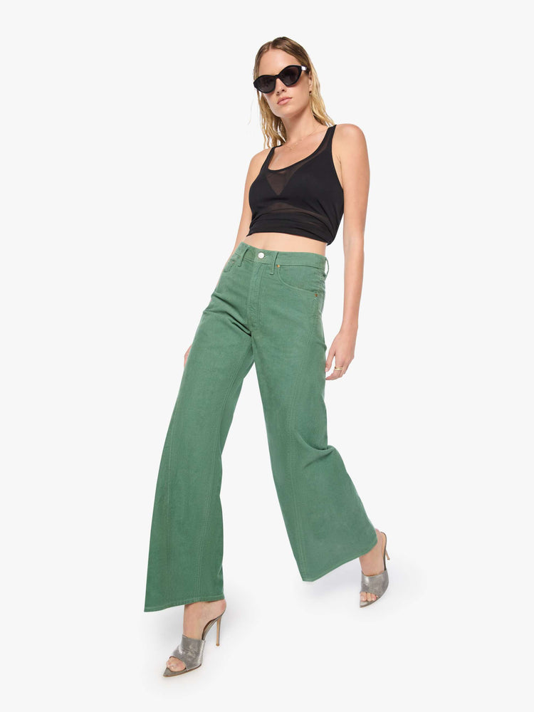 Walking view of a woman in wide leg corduroy designed to sit on the hips with a slouchy fit, these high-rise pants have a zip fly, a loose wide leg with a curved outer seam and a 32-inch inseam with a clean hem.