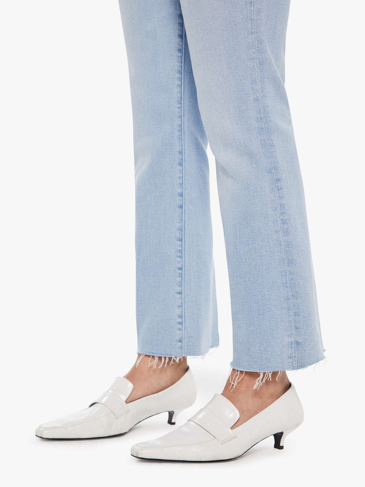 Hem view of a woman in a light blue high-rise flare has an ankle-length inseam and a raw hem.