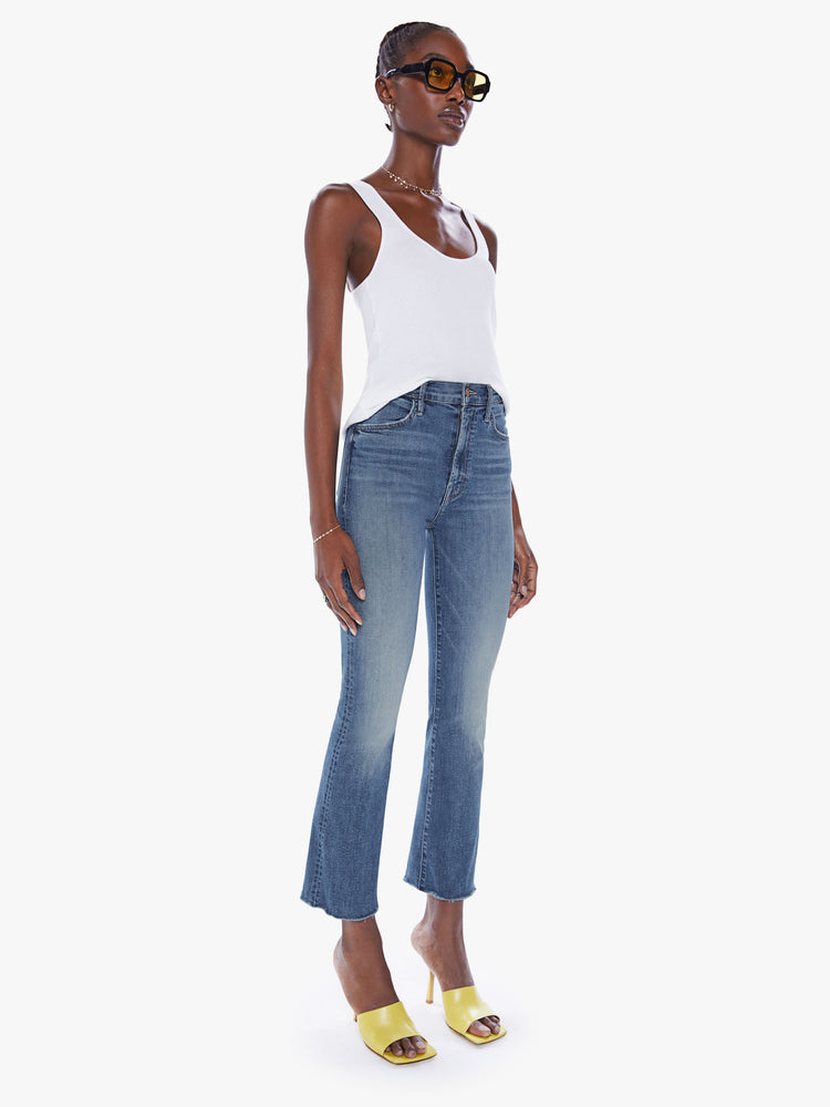 Front view of a womens medium blue wash jean featuring a high rise, flare leg, and a raw ankle length hem.