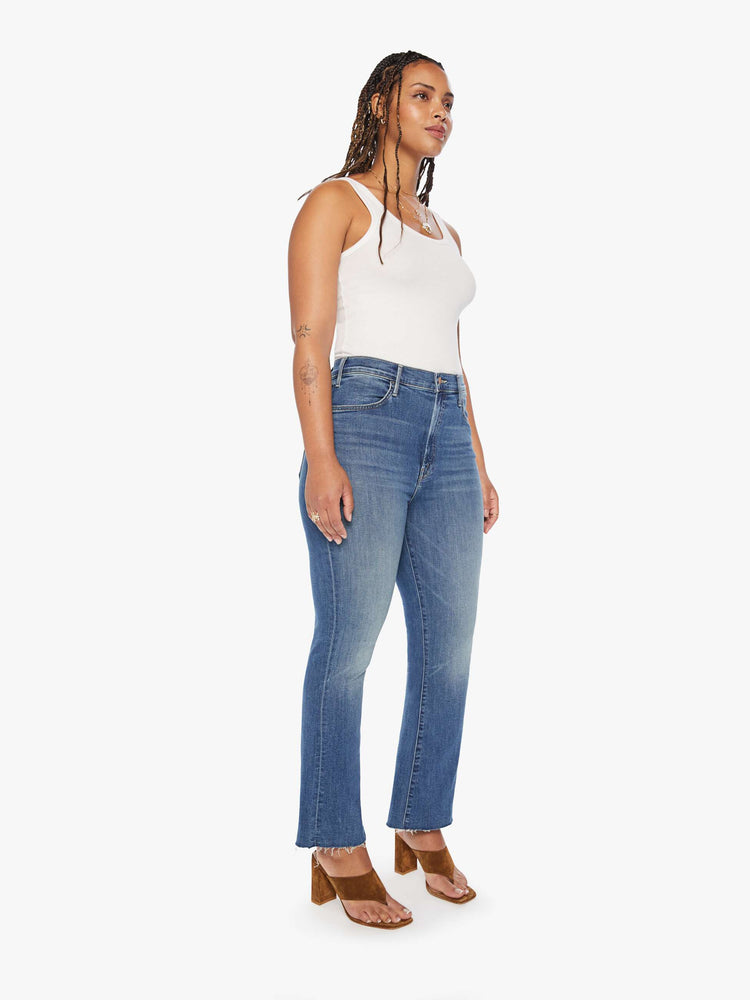 Front view of a womens medium blue wash jean featuring a high rise, flare leg, and a raw ankle length hem.