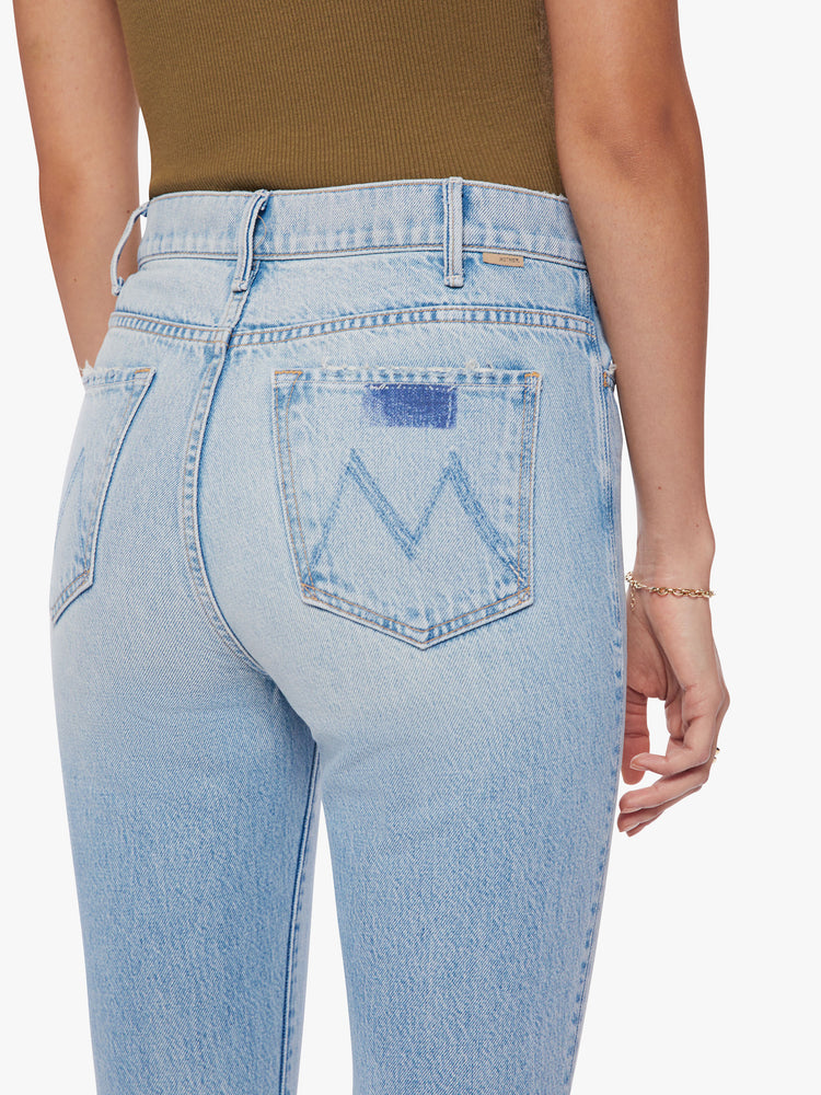 Close up back view of a woman light blue high-rise flare has an ankle-length inseam and a raw hem.