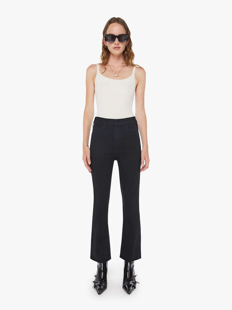 Front view of a womens black jean featuring a high rise, a flare leg, and an ankle length raw hem.