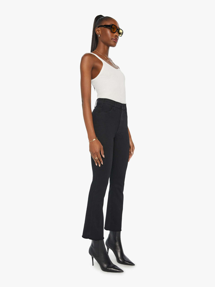 Front 3/4 view of a womens black jean featuring a high rise, a flare leg, and an ankle length raw hem.