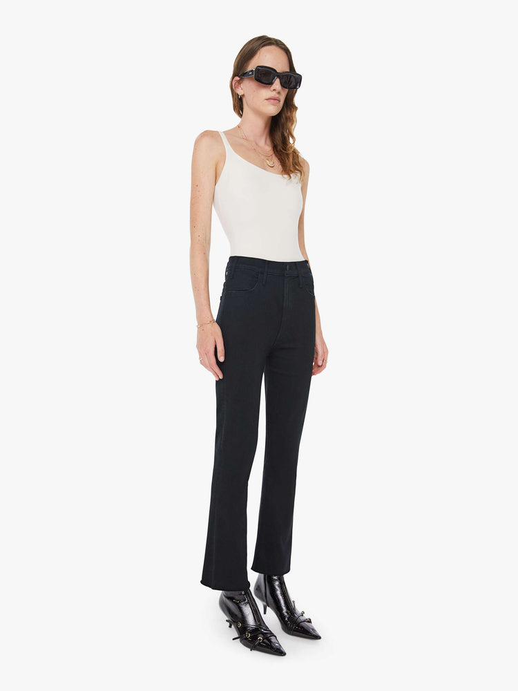 Front 3/4 view of a womens black jean featuring a high rise, a flare leg, and an ankle length raw hem.