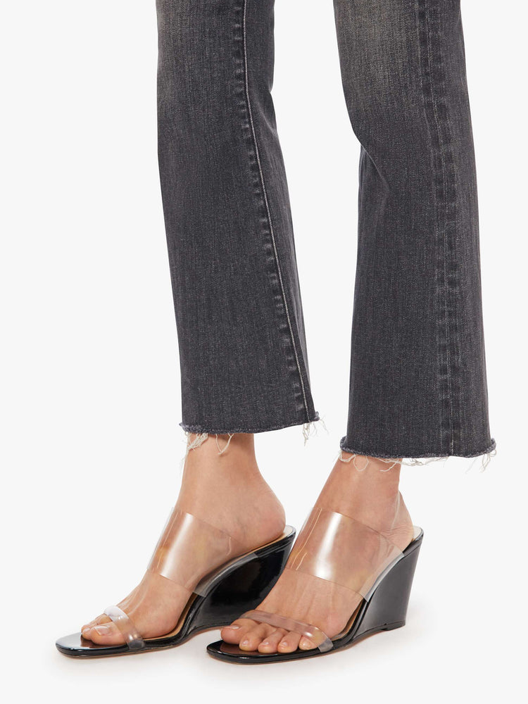 Hem view of women’s faded black cropped bootcut denim.