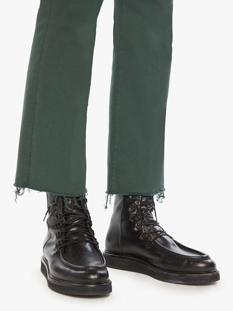 Hem view of a woman high-rise flare has an ankle-length inseam and a raw hem in a forest green.