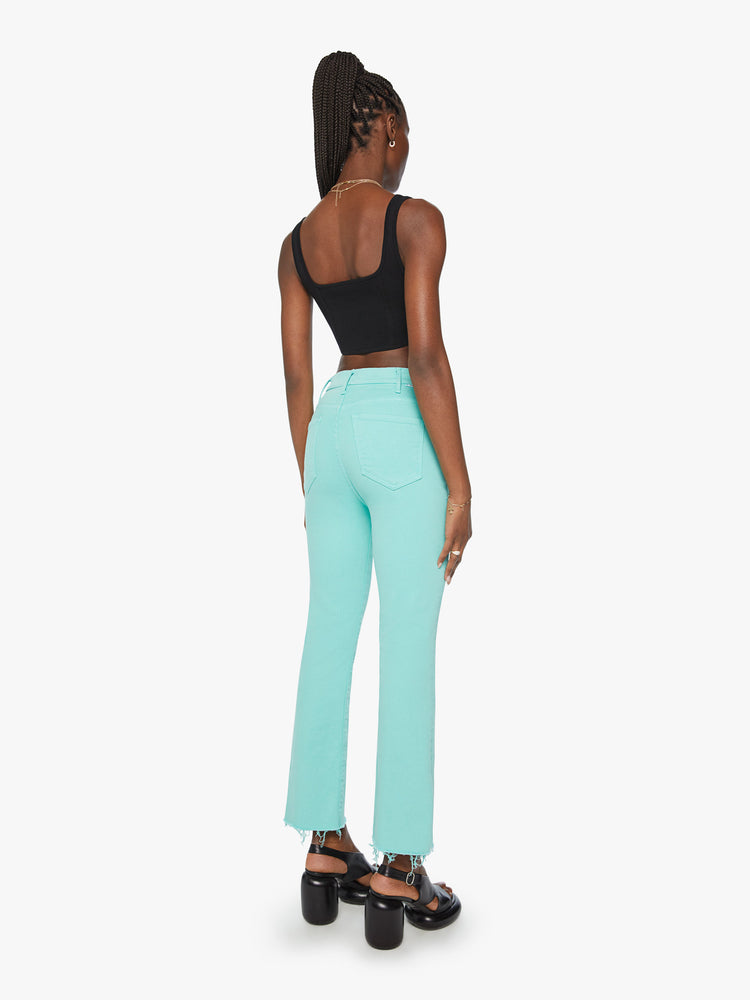 Back view of a woman high-rise flare has an ankle-length inseam and a raw hem in a light blue aqua blue.