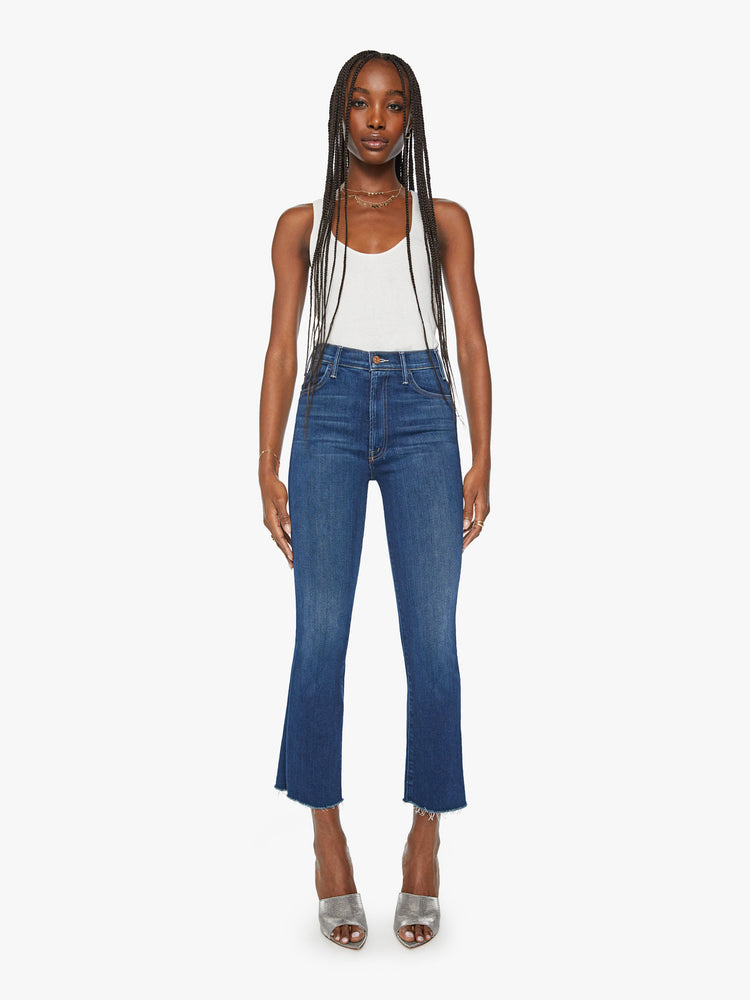 Front view of a womens dark blue wash jean featuring a high rise and an ankle length flare with raw hem.