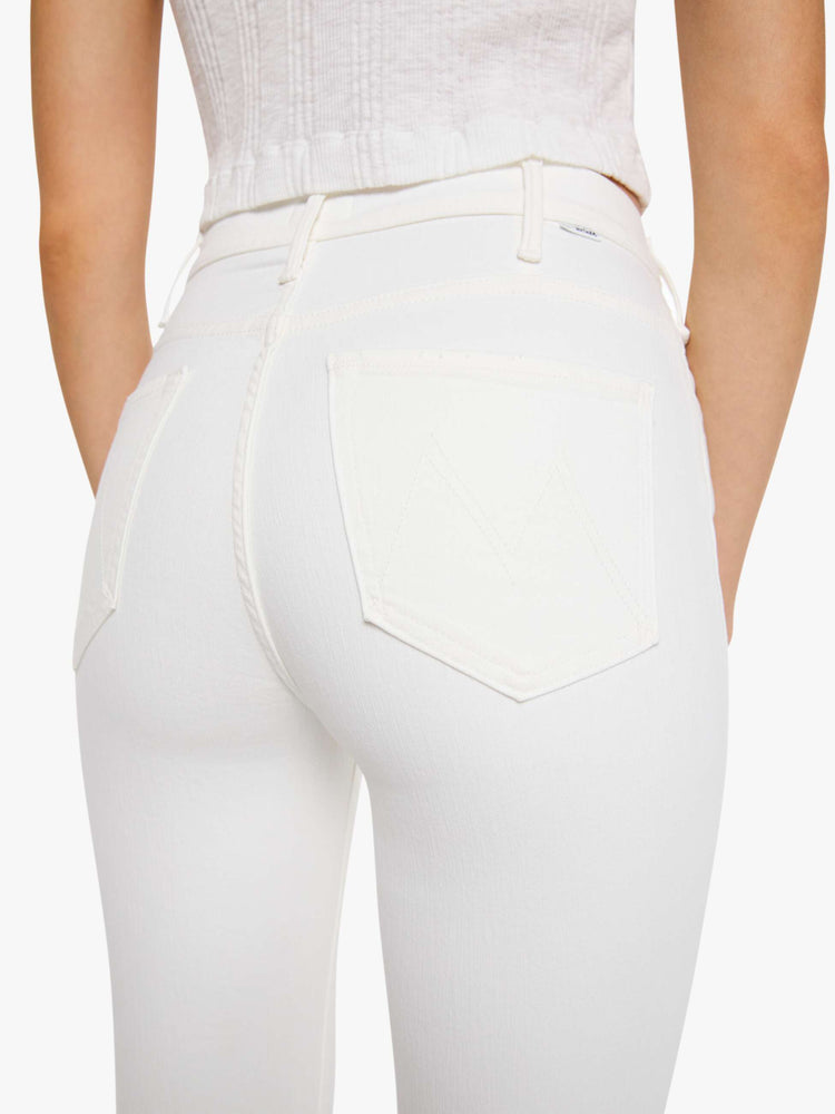 Close up  view of a womens white wash jean featuring a high rise, flare leg, and a frayed hem