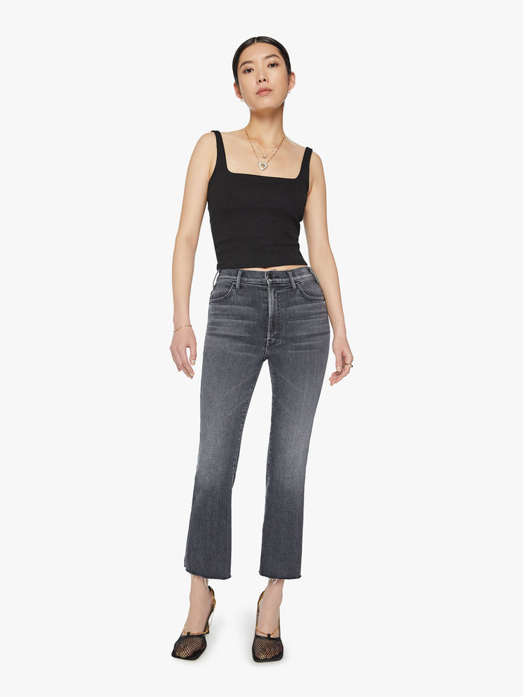 Front view of woman high-rise flare has an ankle-length inseam and a raw hem in a faded black.