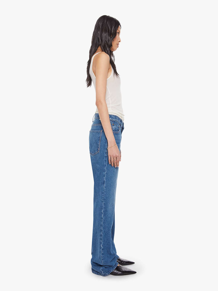 Side view of a woman in mid blue  low-slung jeans with a zip fly, long 33-inch inseam with a loose leg and slouchy fit. 