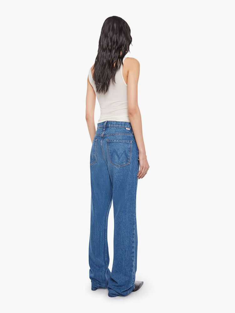 Back view of a woman in mid blue  low-slung jeans with a zip fly, long 33-inch inseam with a loose leg and slouchy fit. 