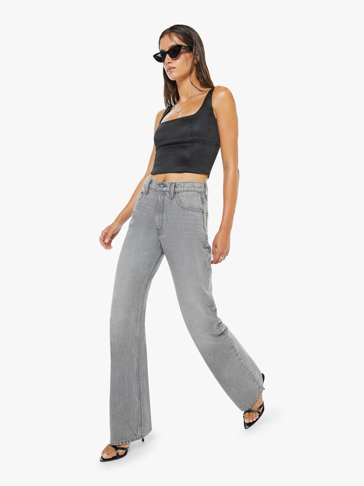 Walking view of a woman in a grey low-slung jeans feature a zip fly, long 33-inch inseam with a loose leg and slouchy fit.