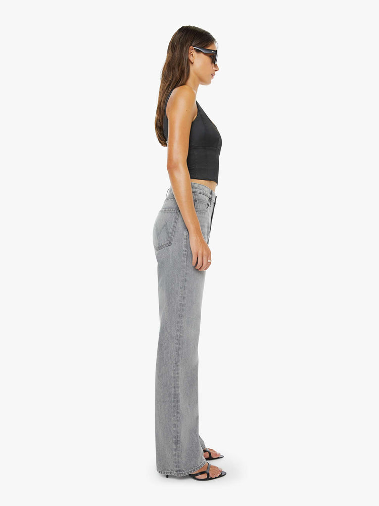 Side view of a woman in a grey low-slung jeans feature a zip fly, long 33-inch inseam with a loose leg and slouchy fit.