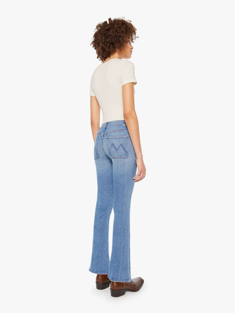 Back view of a woman in  a mid rise flare, zip fly, patch pockets, a 31-inch inseam and a clean hem.