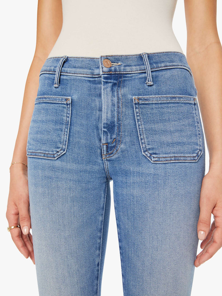 Close up view of a woman in  a mid rise flare, zip fly, patch pockets, a 31-inch inseam and a clean hem.