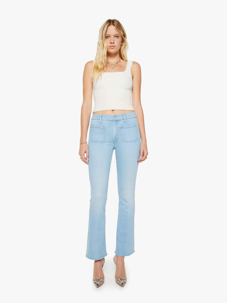 Front view of a woman in a light blue  flare has a mid rise, zip fly, patch pockets, a 31-inch inseam and a clean hem. 