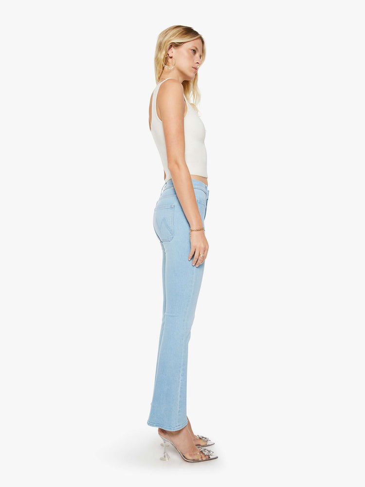 Side view of a woman in a light blue  flare has a mid rise, zip fly, patch pockets, a 31-inch inseam and a clean hem. 