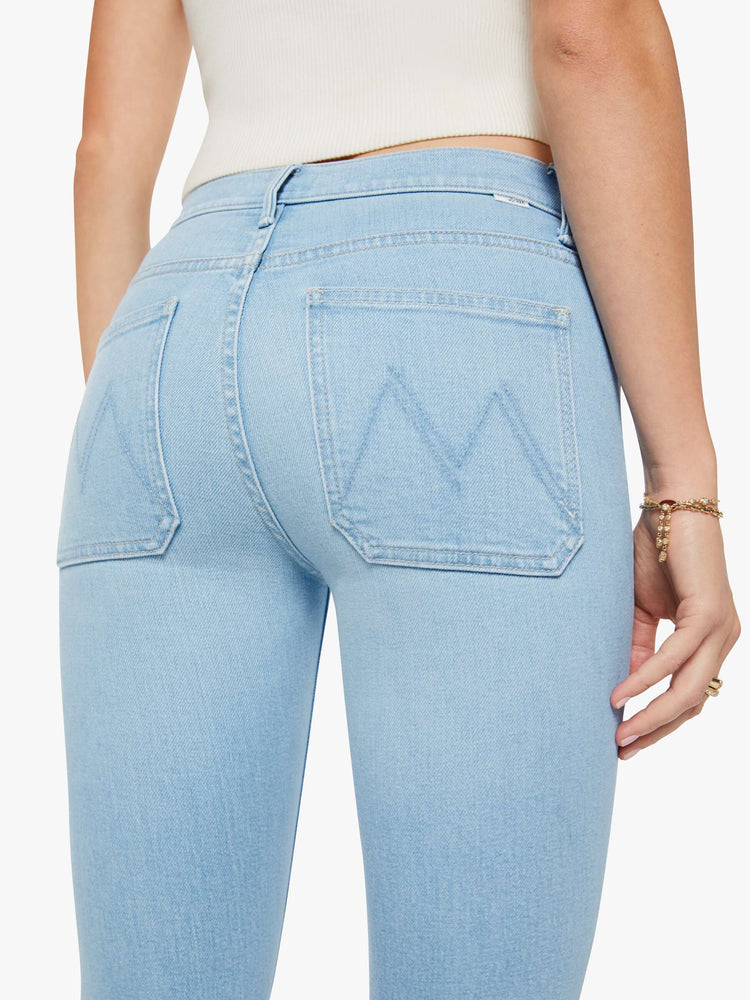 Back close up view of a woman in a light blue  flare has a mid rise, zip fly, patch pockets, a 31-inch inseam and a clean hem. 
