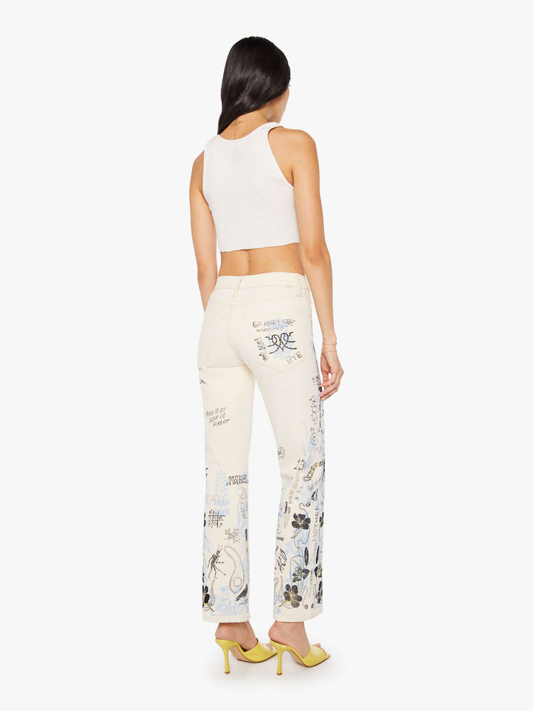 Back view of a woman in an off white with hand drawn doodles in light blue and black mid-rise jeans with a wide straight leg, zip fly and clean 30-inch inseam.