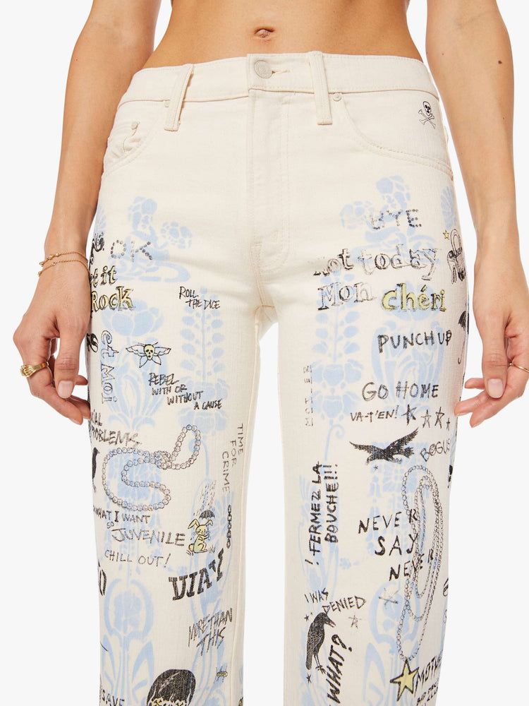 Close up view of a woman in an off white with hand drawn doodles in light blue and black mid-rise jeans with a wide straight leg, zip fly and clean 30-inch inseam.
