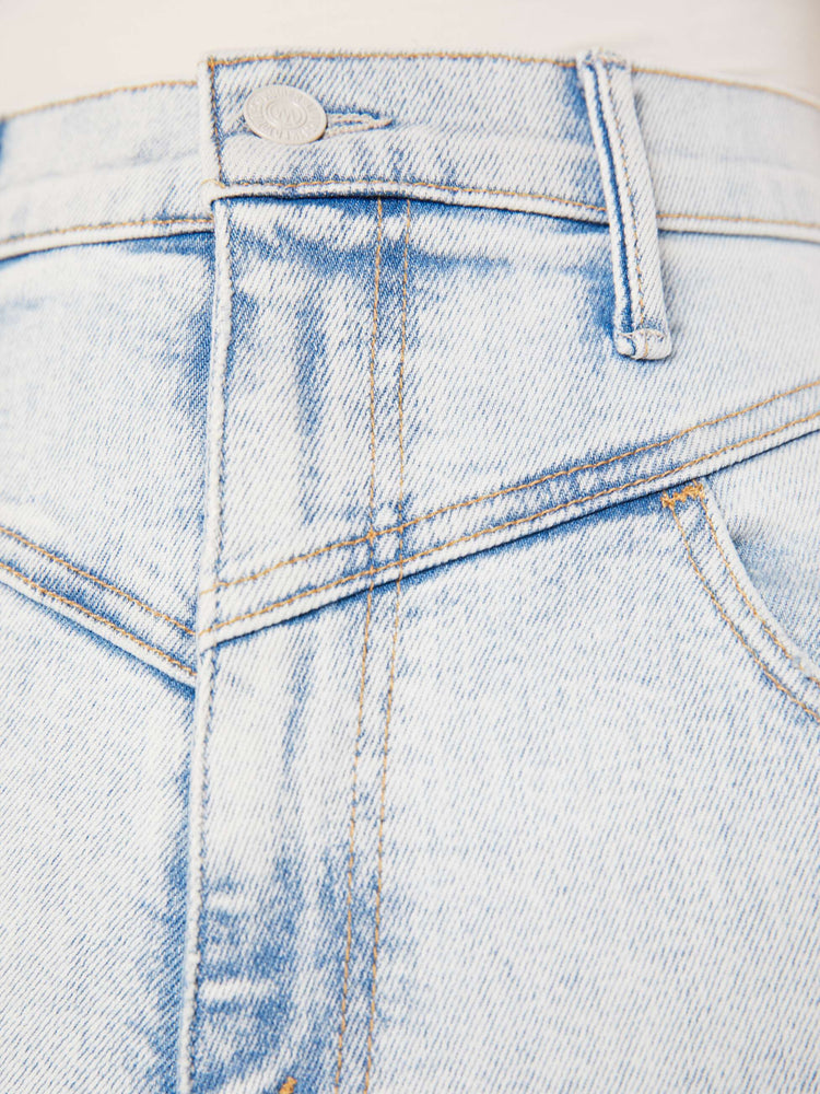 Close up swatch detail view of pair of light blue acid wash jeans, featuring angled seam details.