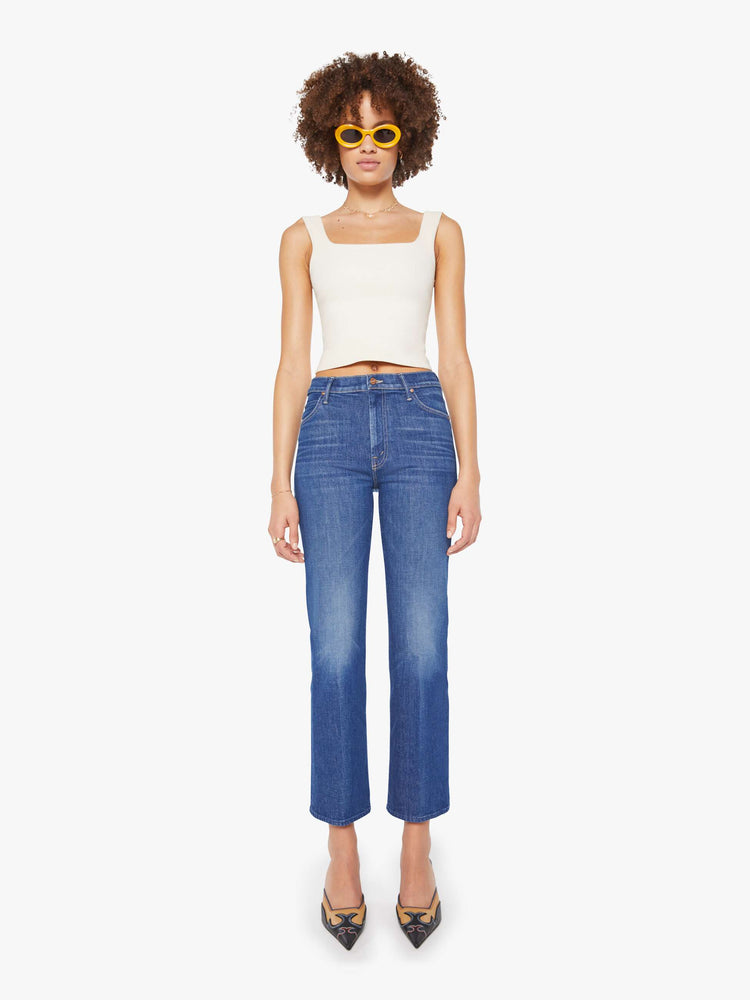 Front view of a woman in a mid blue high-rise straight leg jean with a zip fly, 28.25-inch inseam and a clean hem.