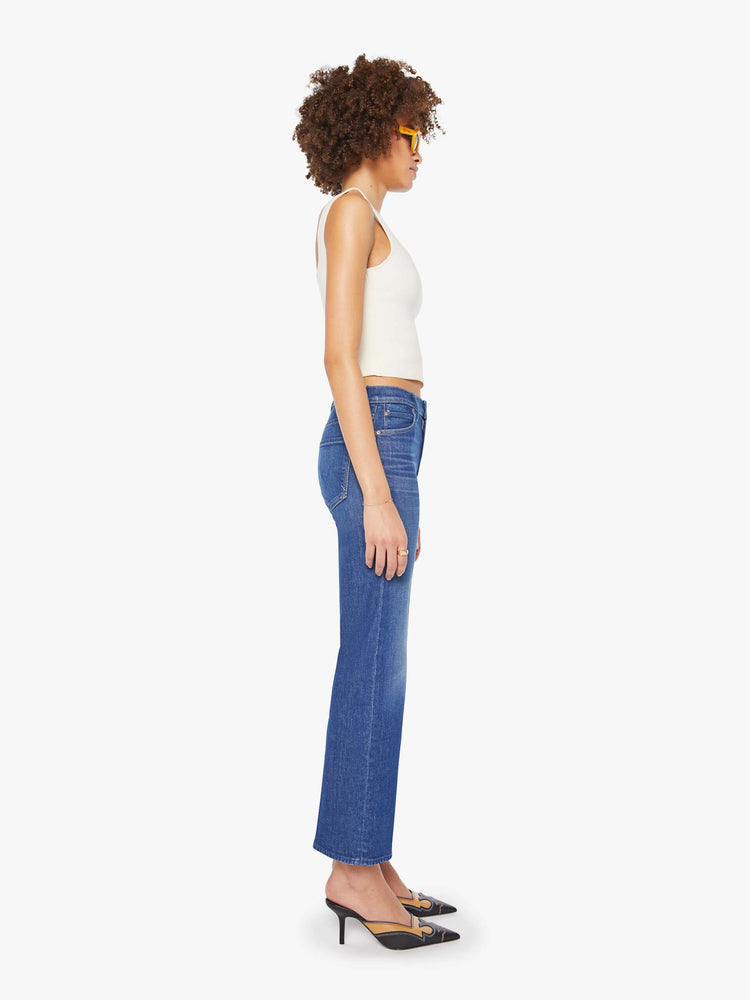 Side view of a woman in a mid blue high-rise straight leg jean with a zip fly, 28.25-inch inseam and a clean hem.