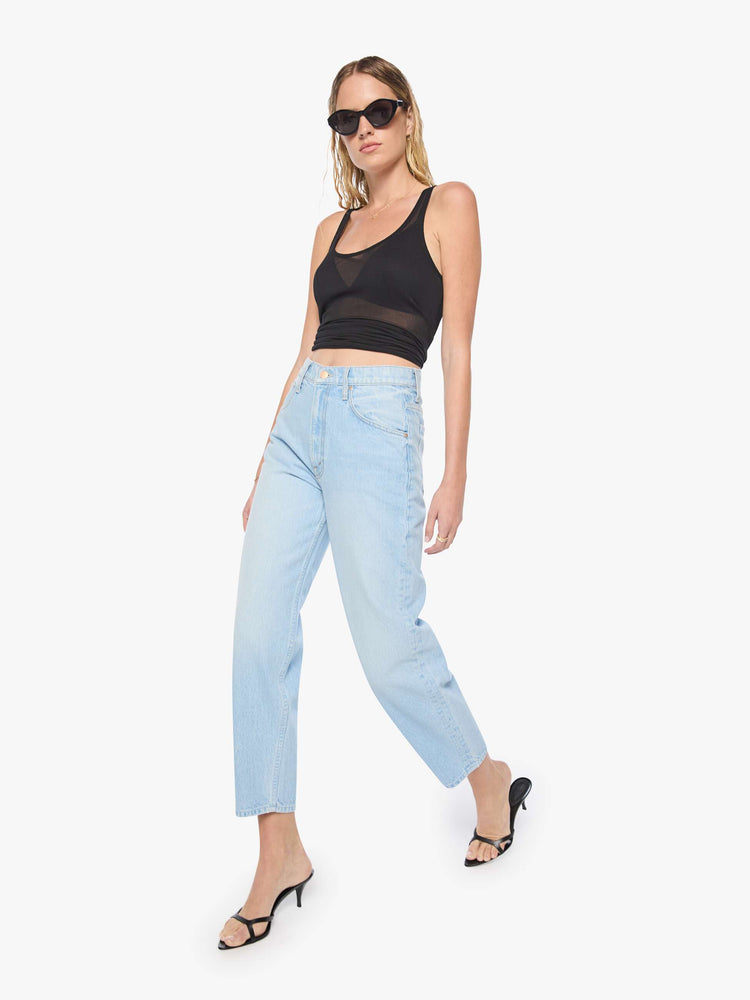 Walking view of a woman in light blue denim with a straight super high-waisted pants have a zip fly and an ankle-length inseam.