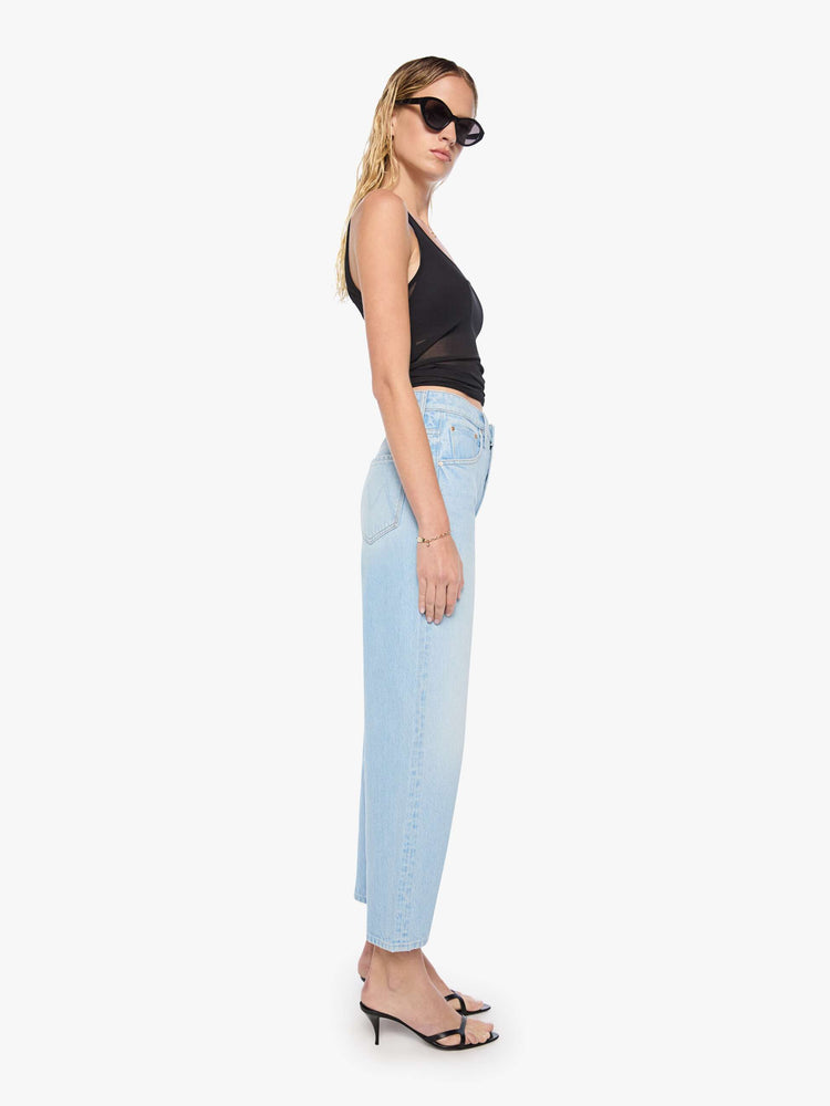 Side view of a woman in light blue denim with a straight super high-waisted pants have a zip fly and an ankle-length inseam.