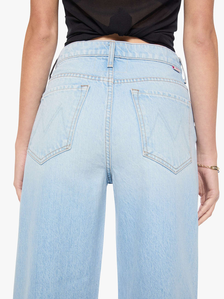 Close up view of a woman in light blue denim with a straight super high-waisted pants have a zip fly and an ankle-length inseam.