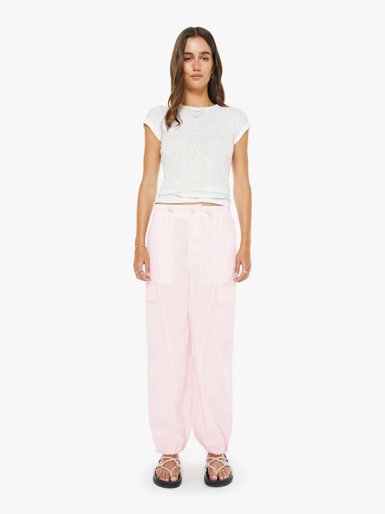 Front view of a woman in pink wide-leg pants with an elastic drawstring waist, patch pockets on the thighs, seamed details and a long inseam with adjustable elastic hems.