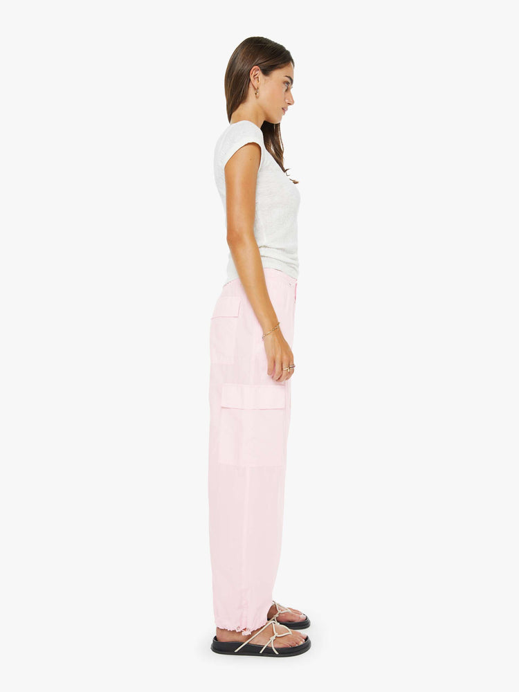 Side view of a woman in pink wide-leg pants with an elastic drawstring waist, patch pockets on the thighs, seamed details and a long inseam with adjustable elastic hems.