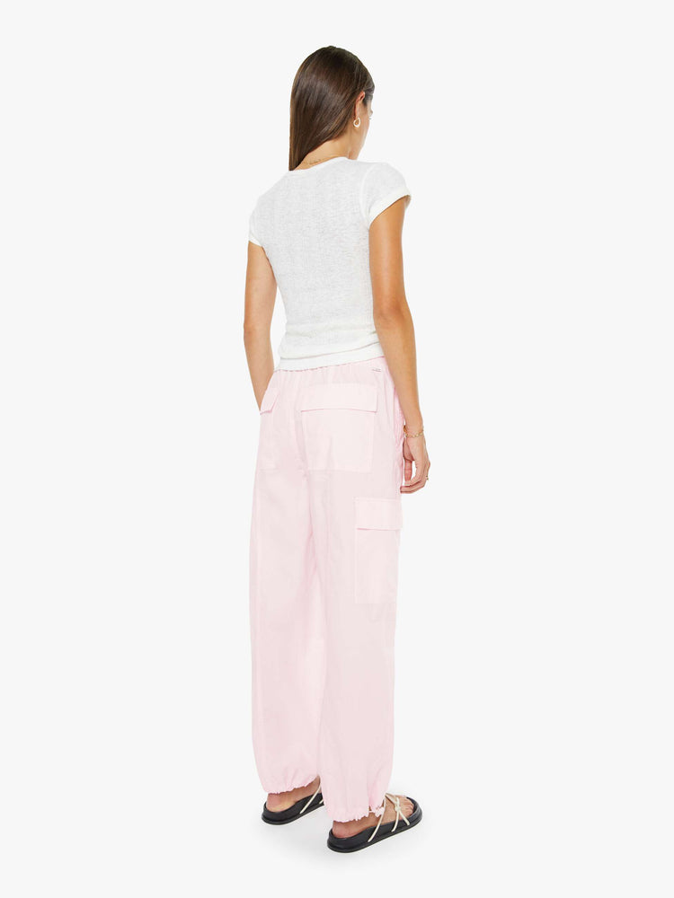 Back view of a woman in pink wide-leg pants with an elastic drawstring waist, patch pockets on the thighs, seamed details and a long inseam with adjustable elastic hems.