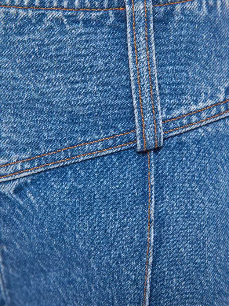 Swatch view of a woman in a mid blue  low-rise jeans feature an extra-wide waistband with a side-zip closure, a slightly flared leg with pintuck details down the front and a long 34-inch inseam with a clean hem. 