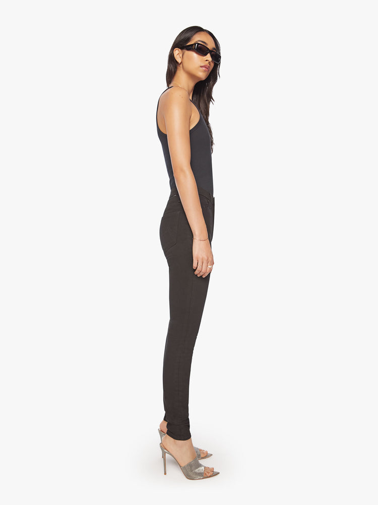 Side view of a womens black skinny jean, featuring a high rise and a clean hem.