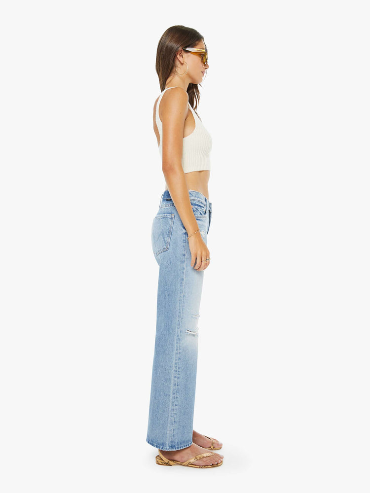 Side  view of a woman in a light blue  mid-rise bootcut with a zip fly, looser leg and a 30-inch inseam with a clean hem. 