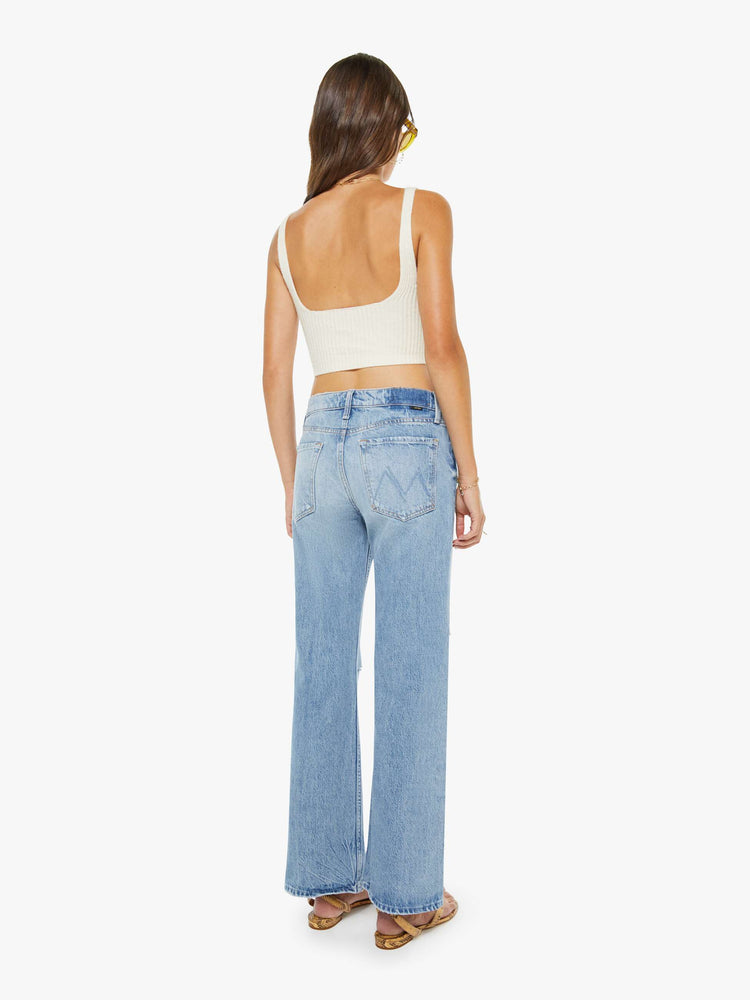 Back  view of a woman in a light blue  mid-rise bootcut with a zip fly, looser leg and a 30-inch inseam with a clean hem. 