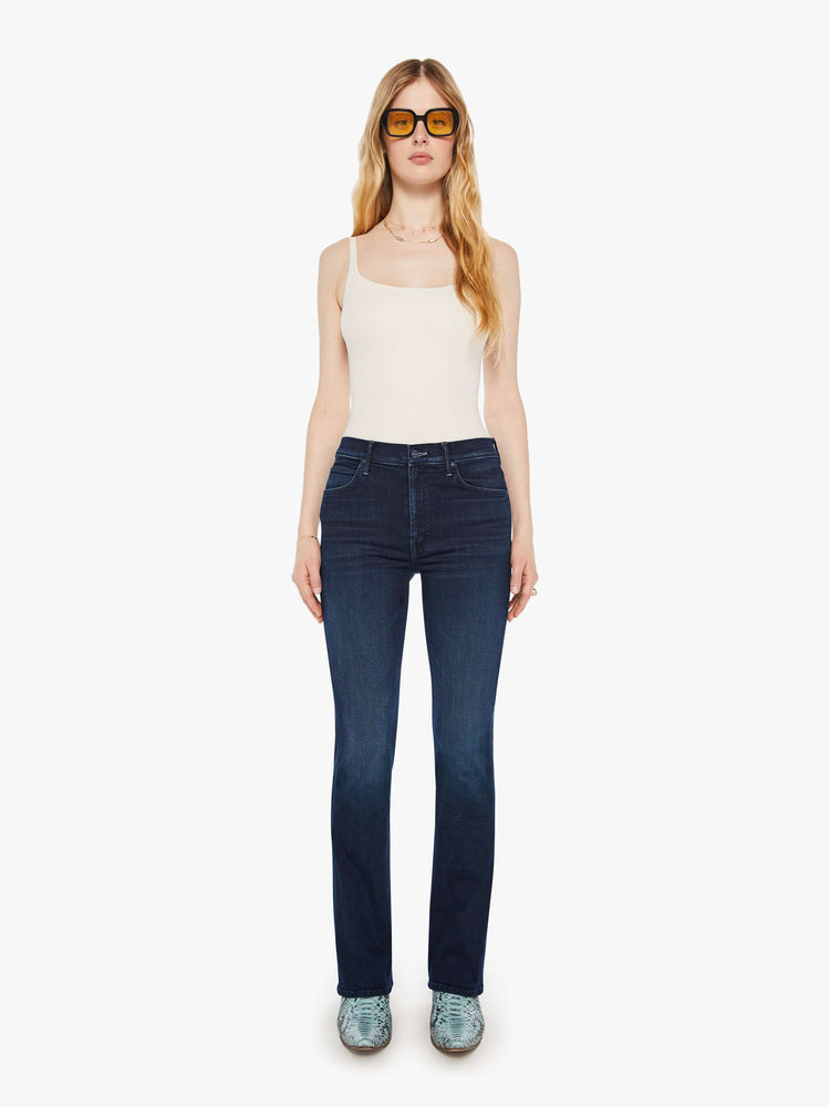 Front view of a woman in a dark blue mid-rise jeans with a flared leg, zip fly and a long 31-inch inseam with a clean hem. 
