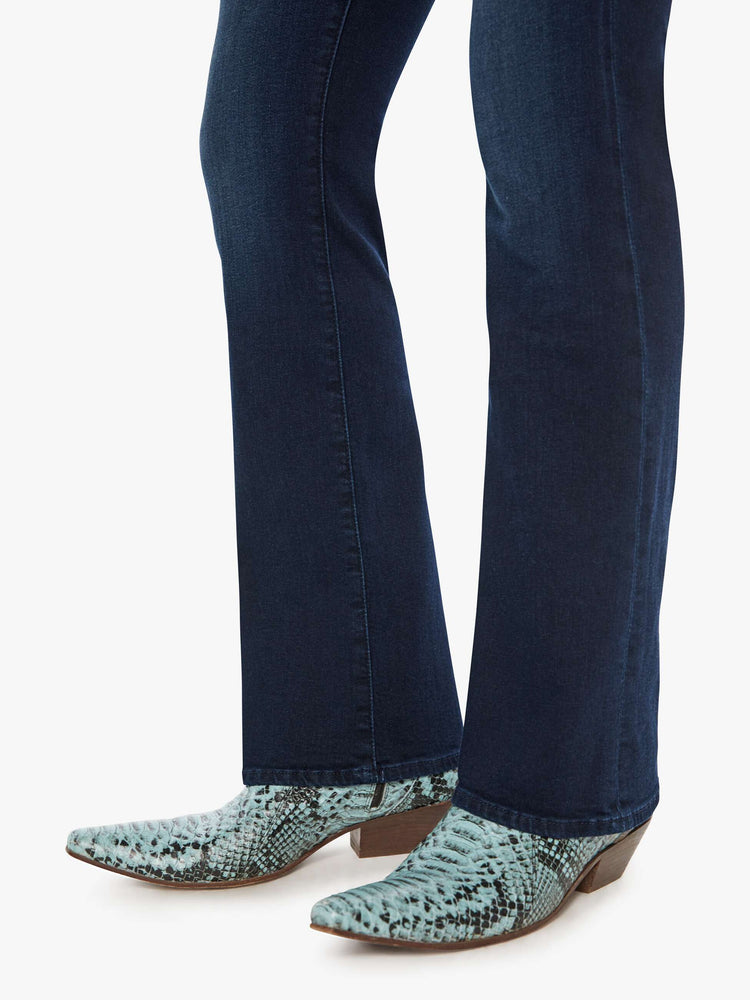 Hem view of a woman in a dark blue mid-rise jeans with a flared leg, zip fly and a long 31-inch inseam with a clean hem. 