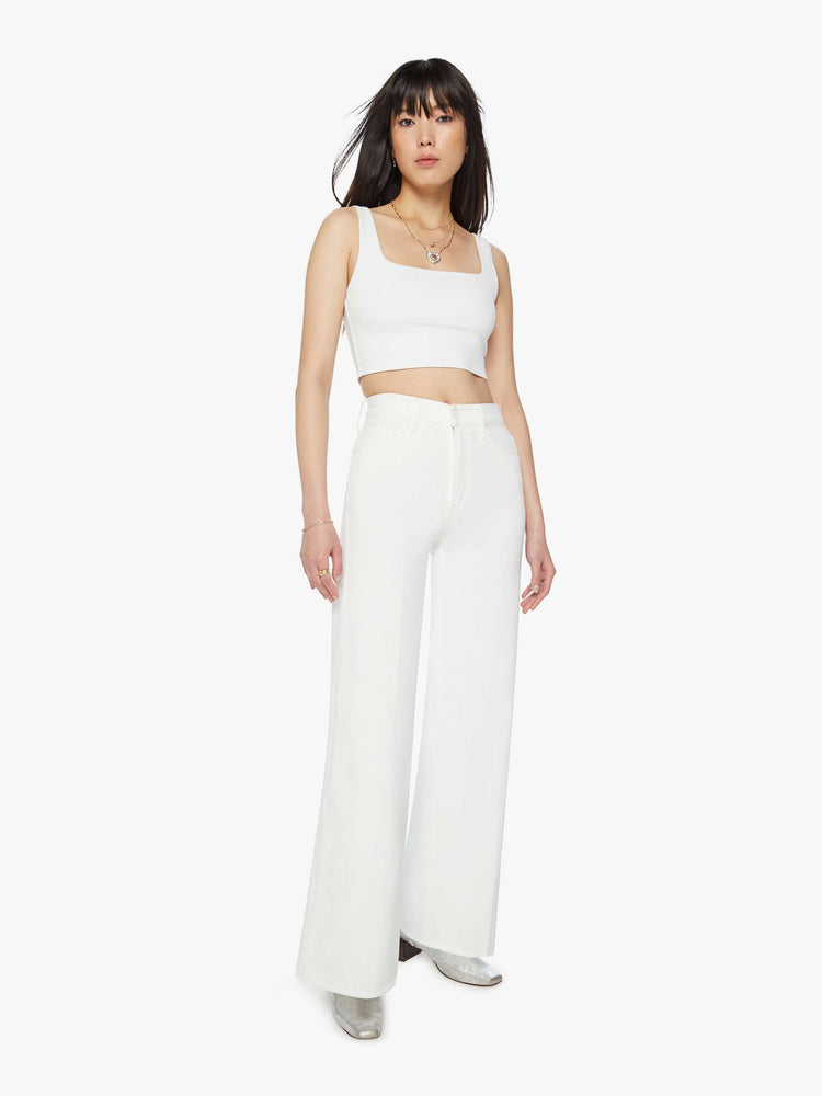 Front view of a woman white wide leg pants with a high rise, long 32-inch inseam and a frayed hem.
