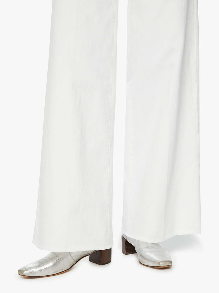 Close up detail view of a woman white wide leg pants with a high rise, long 32-inch inseam and a frayed hem.